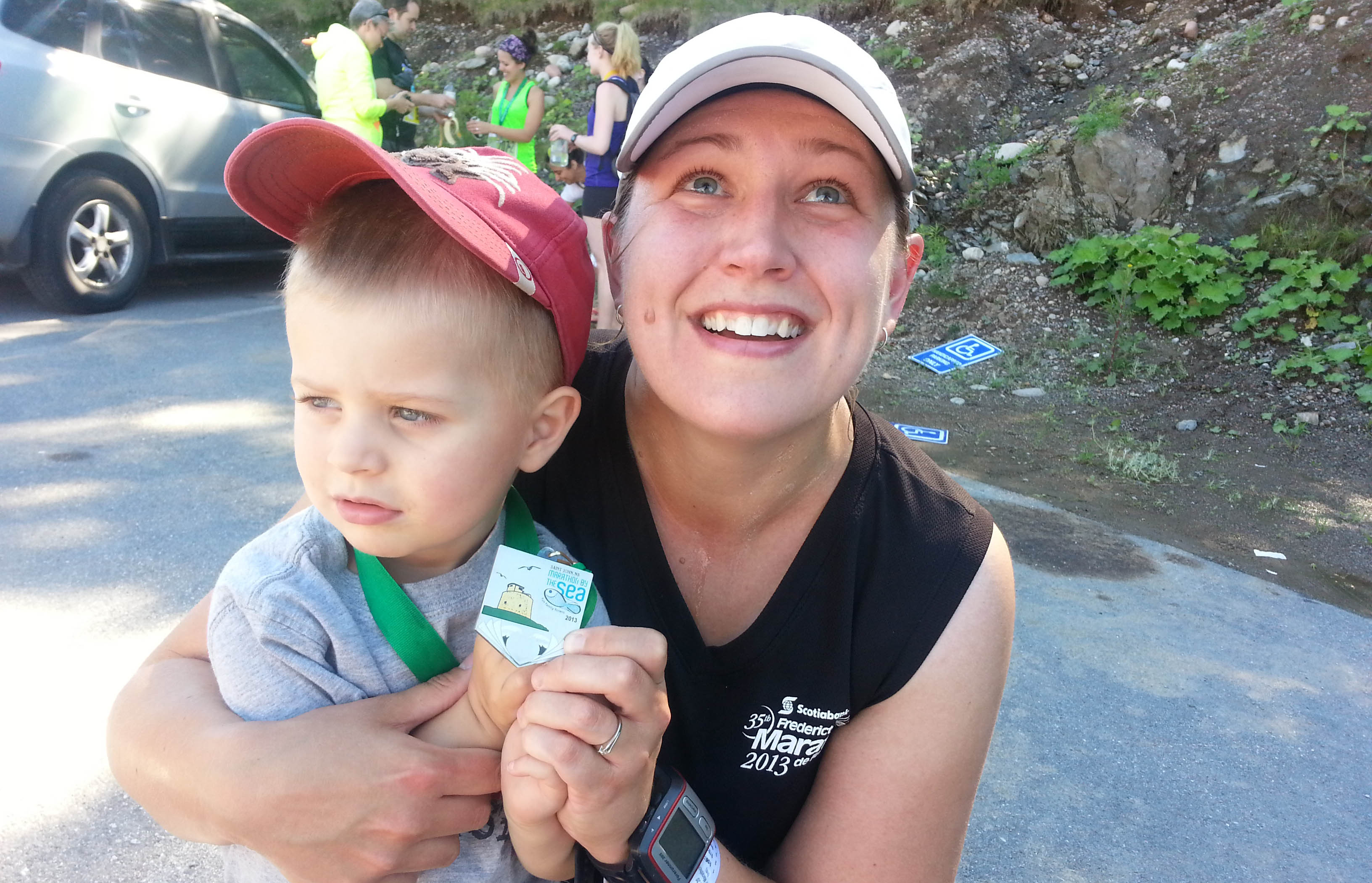 An emotional Samantha MacAlpine holds her son at the finish line of the 2013 Marathon by the Sea half marathon. Earlier that morning, she learned her grandfa-ther passed away. She wears his dog tags as a good luck charm when she runs.